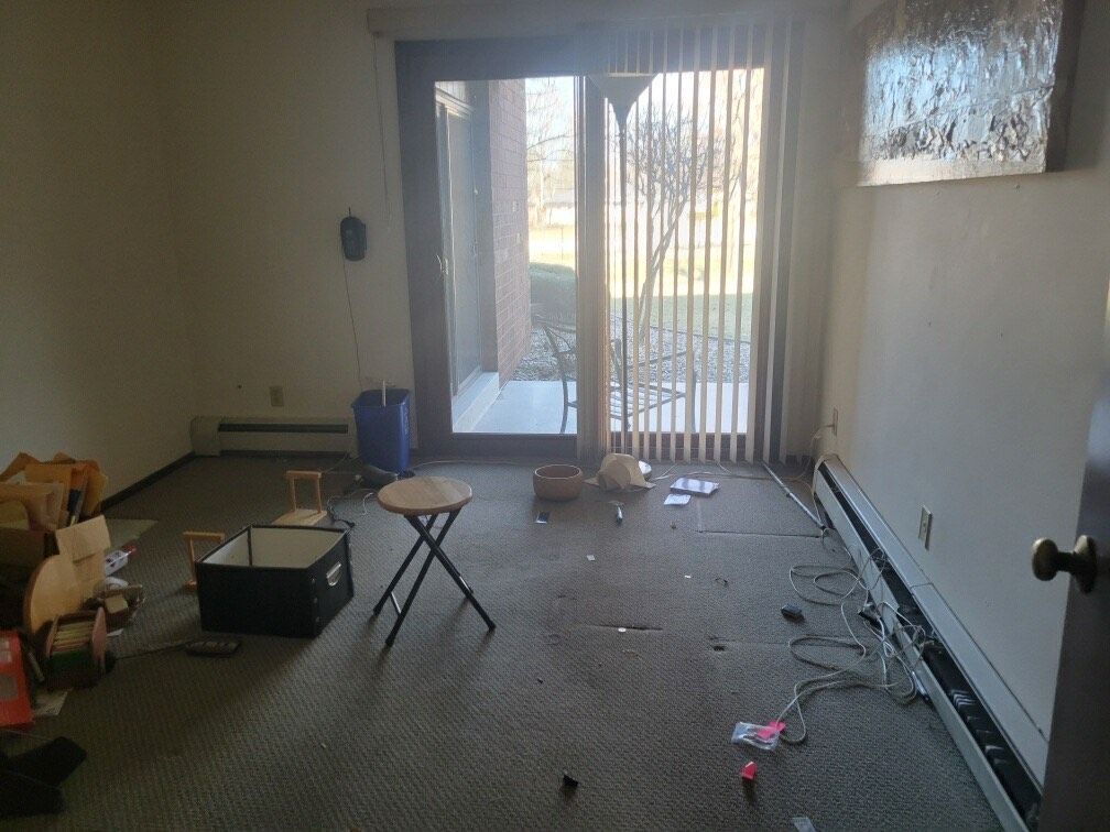 An empty living room with a sliding glass door and blinds.