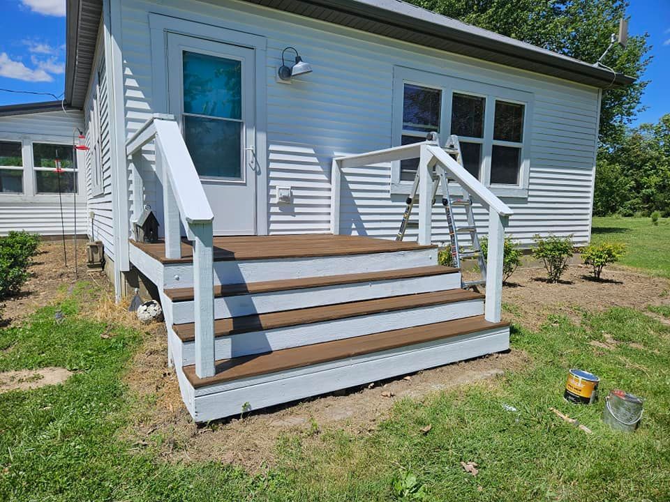 White house back steps with a small wooden deck, white railings, and a single door and window.