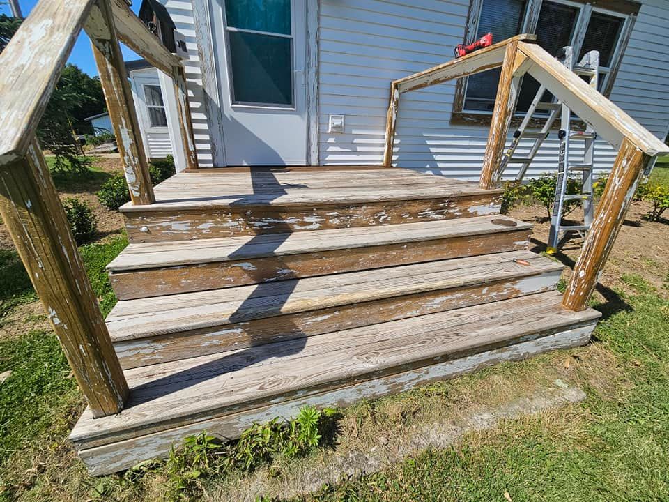 Weathered wooden front steps with handrails leading up to a white house entrance