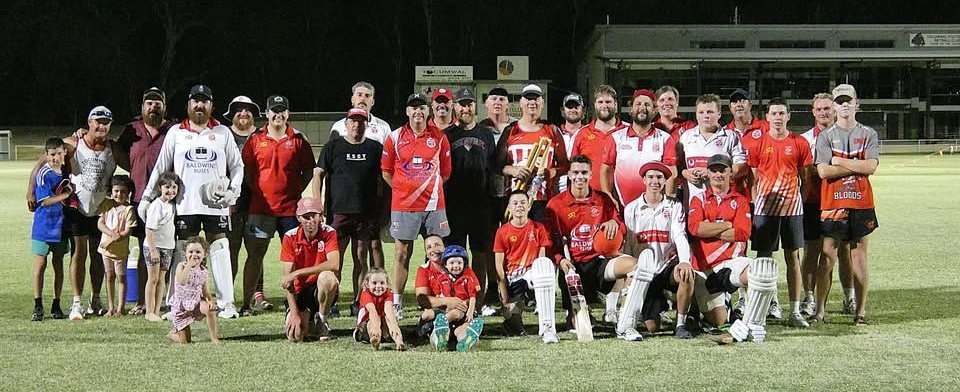 Group of soccer players posing on a field at night, with uniforms in red, white, and black.