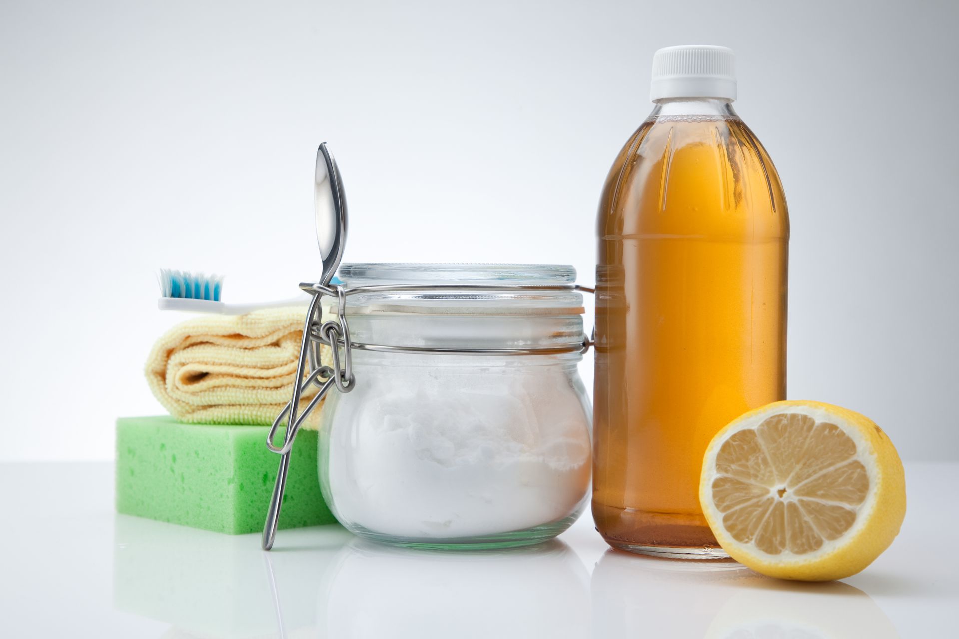 Skincare items with soap, brush, cream jar, amber bottle, and lemon on a white surface