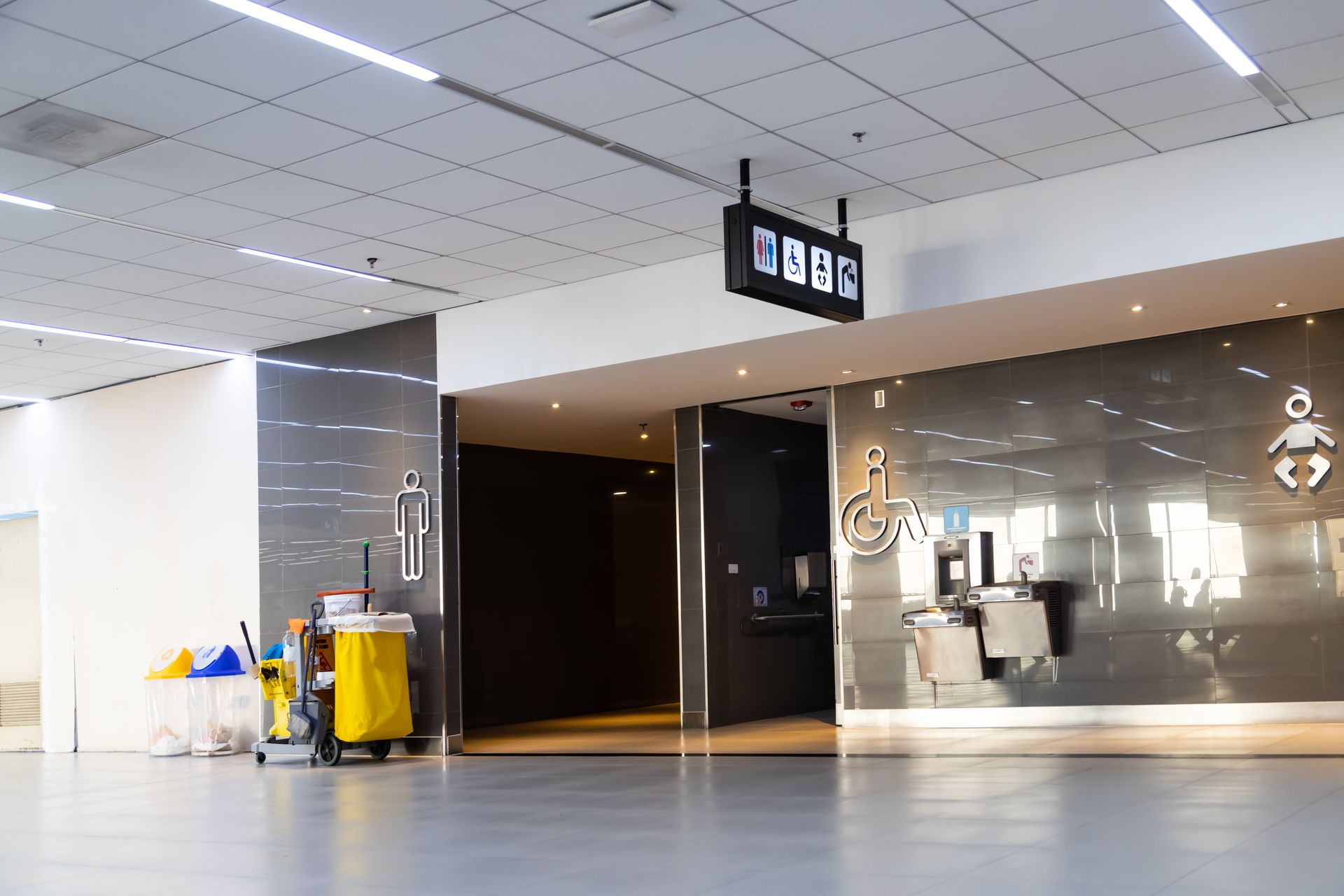 Empty airport terminal with polished floor, ceiling lights, and a digital gate sign above the walkway
