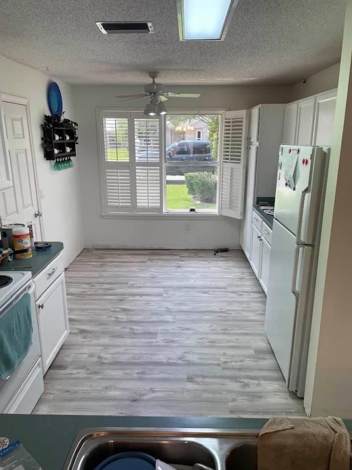 A kitchen with a refrigerator , stove , sink and window.