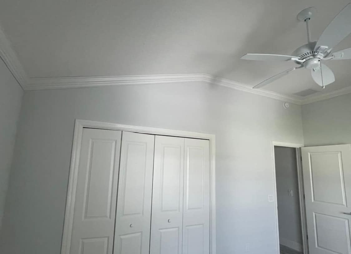 A bedroom with white doors and a ceiling fan