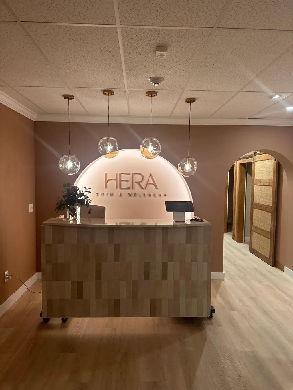 Reception area with light wood counter, globe pendant lights, and 