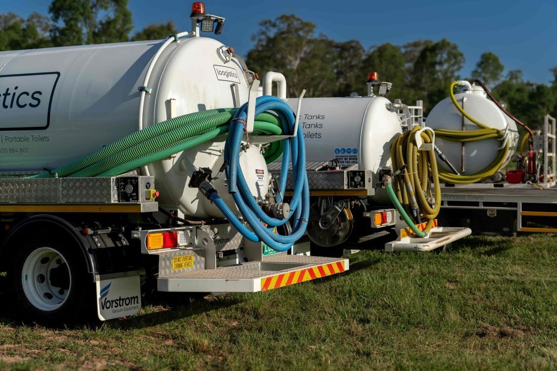 Two White Tanker Trucks With Hoses on a Grassy Area — Loogistics in Coolum Beach, QLD