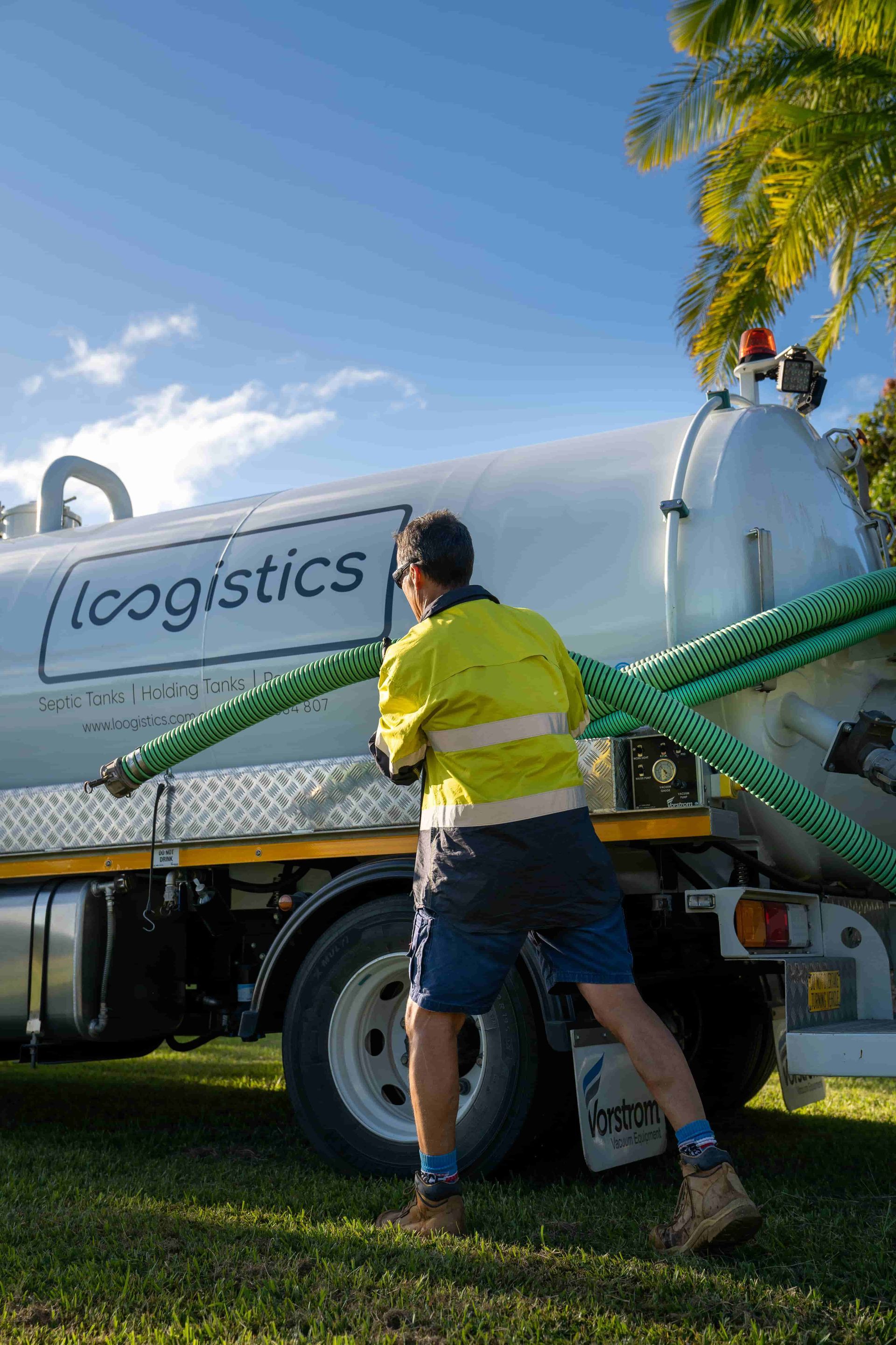 A man is pushing a vacuum truck with a green hose attached to it. — Loogistics in Coolum Beach, QLD