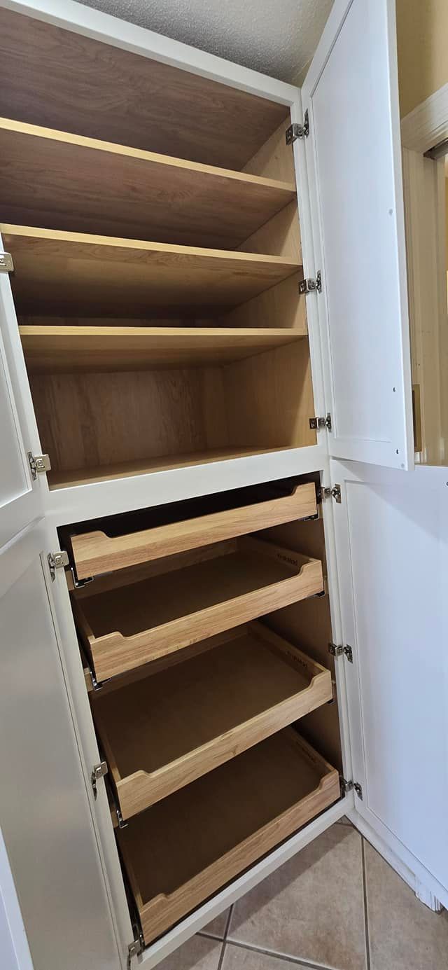 A white cabinet with wooden shelves and drawers in a kitchen.
