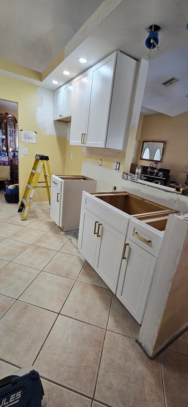 A kitchen is being remodeled with white cabinets and a sink.