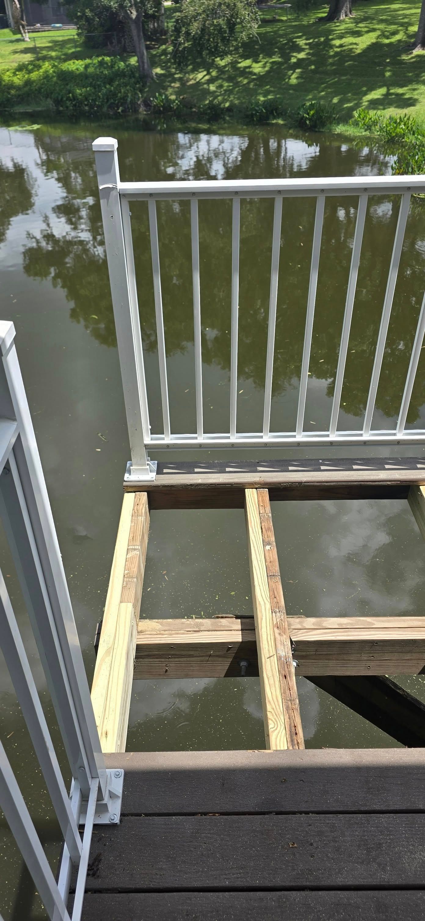 A wooden deck with a metal railing overlooking a body of water.