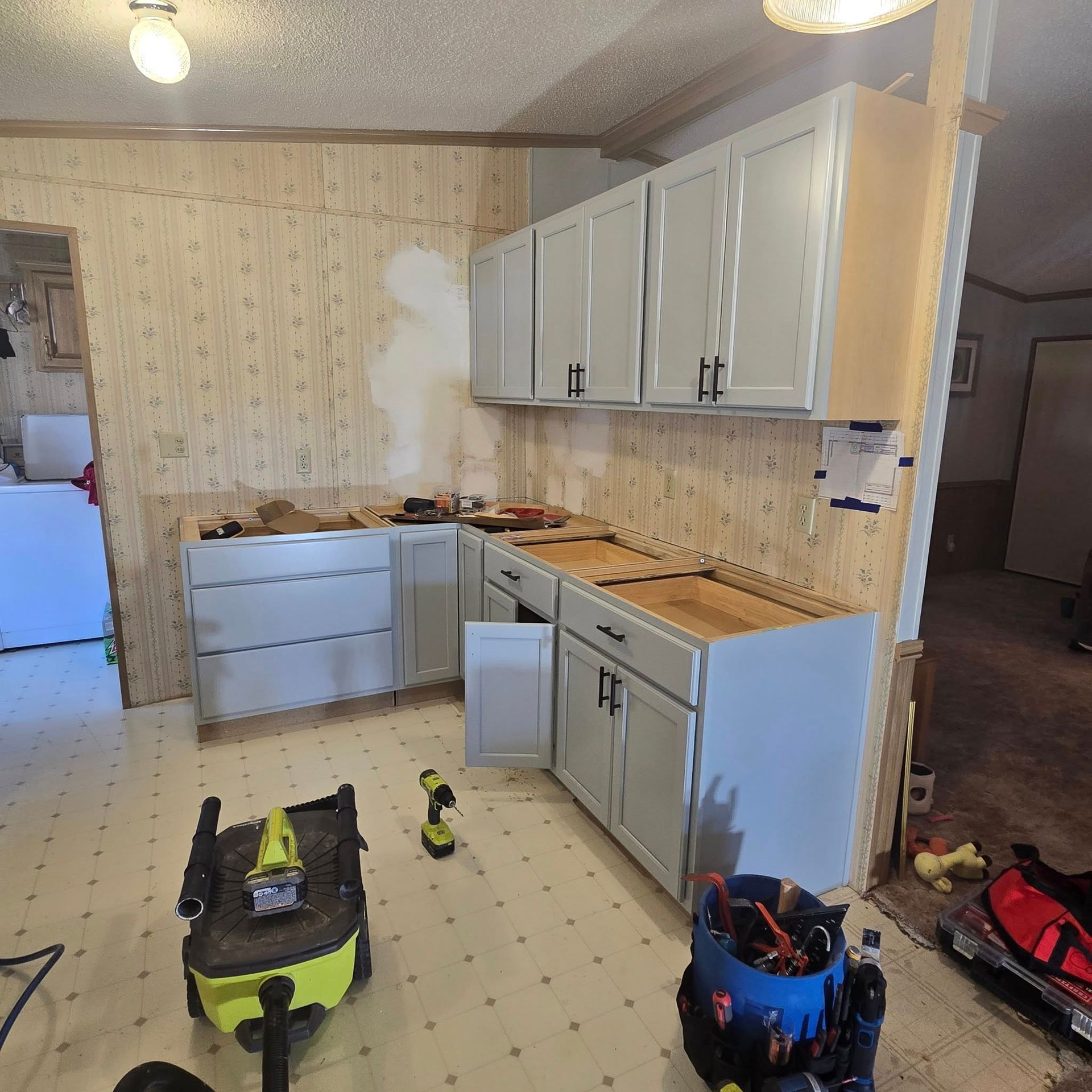 A kitchen with white cabinets and a vacuum cleaner on the floor