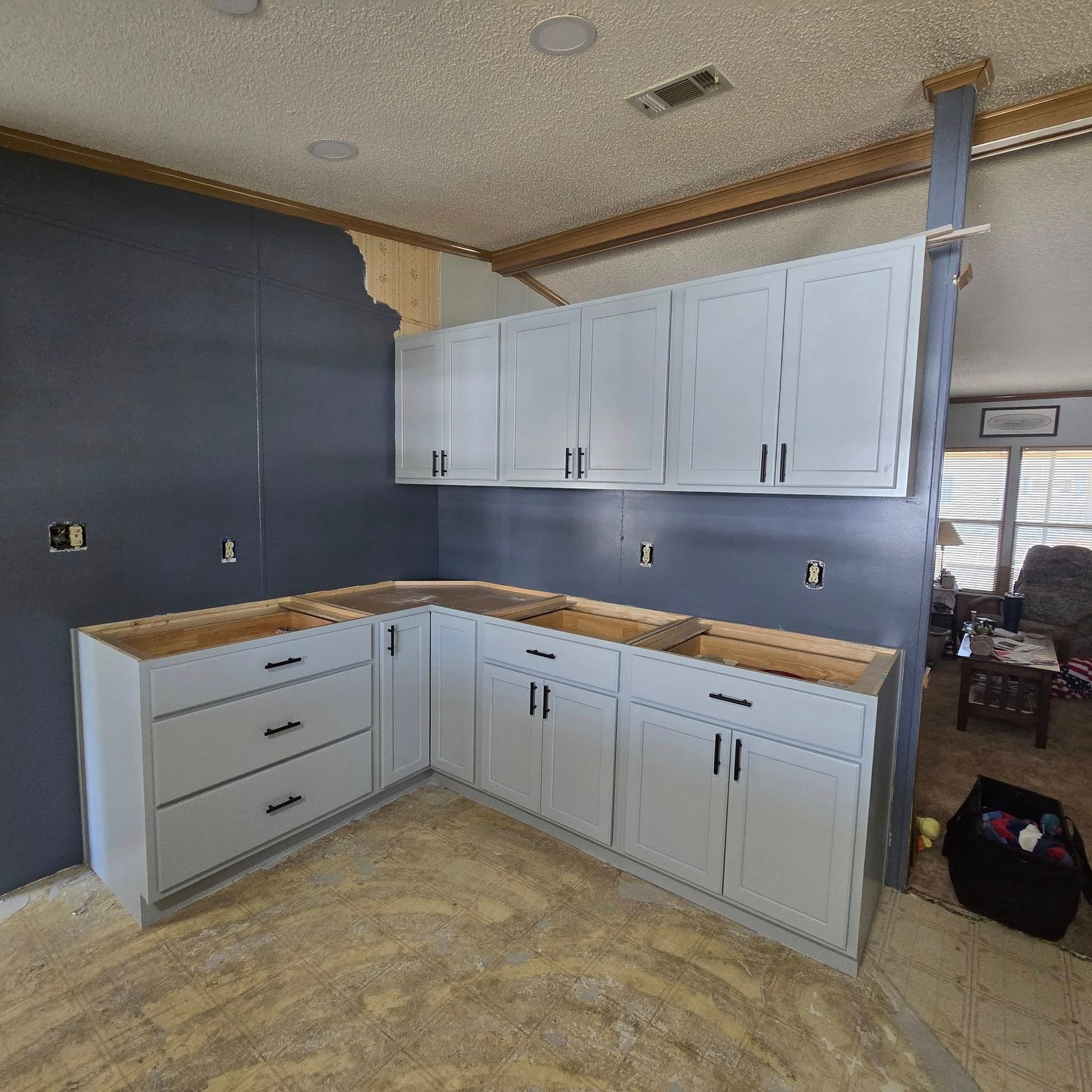 A kitchen under construction with white cabinets and a sink.