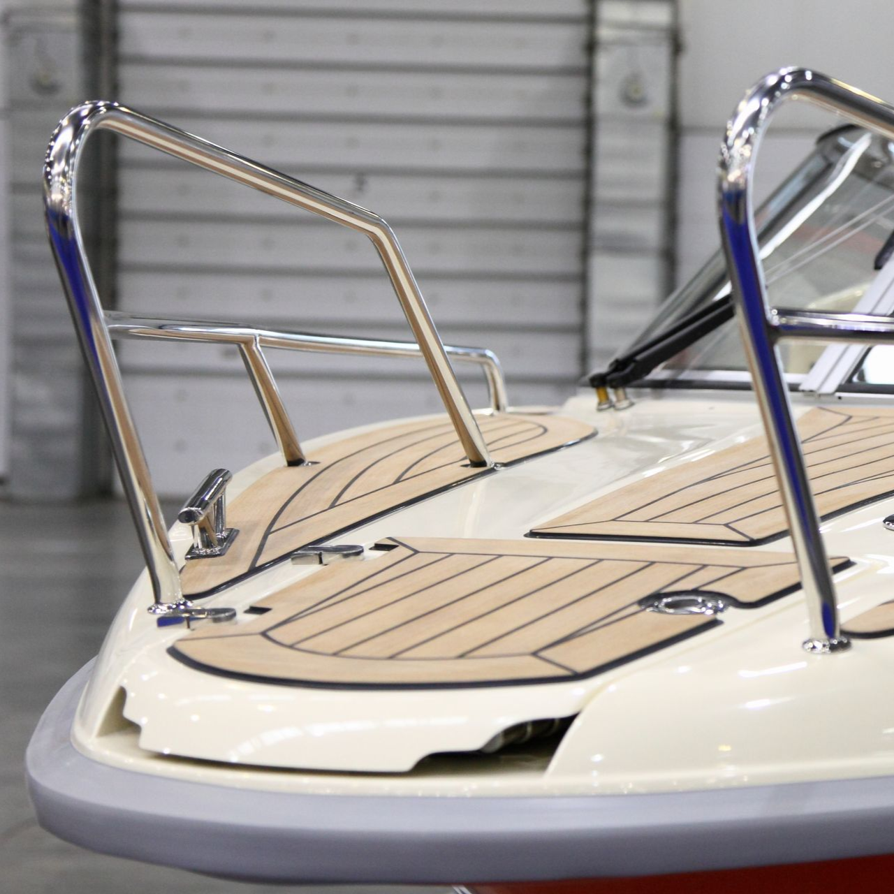 Poupe du bateau avec rambardes en acier inoxydable, pont beige et pare-chocs gris.