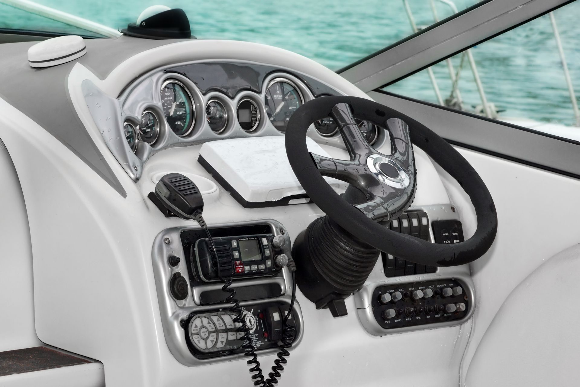 Tableau de bord de bateau avec volant, jauges, radio et commandes.