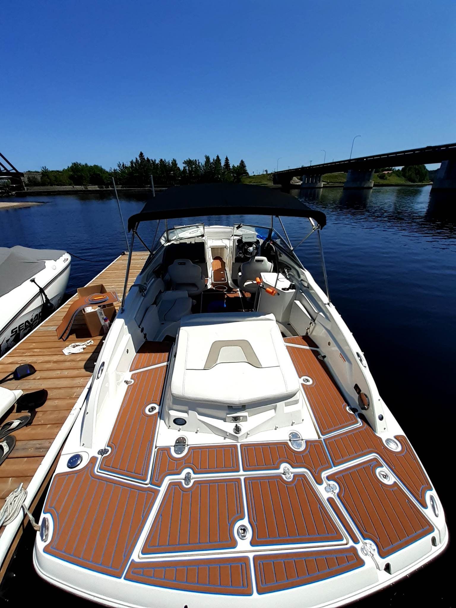 Bateau amarré au quai, pont marron, eau bleue, ciel dégagé, pont en arrière-plan.