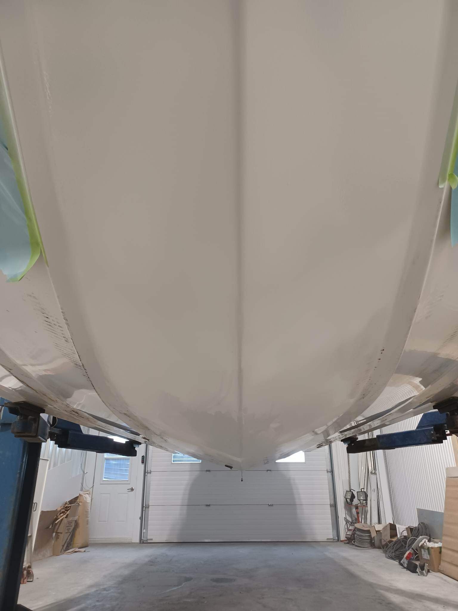 Coque de bateau blanche, vue de dessous, dans un atelier.