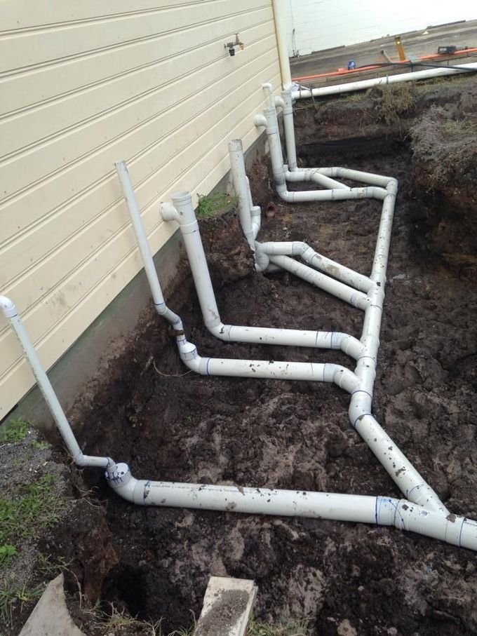 A Bunch Of Pipes Are Laying In The Dirt In Front Of A House — LJG Plumbing In Sarina, QLD