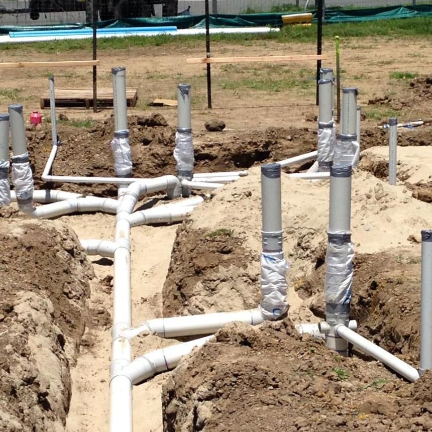 A Bunch Of Pipes Are Laying In The Dirt — LJG Plumbing In Sarina, QLD