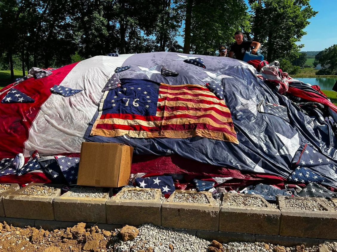 Veterans conducting a flag retirement ceremony around a fire pit at golden hour