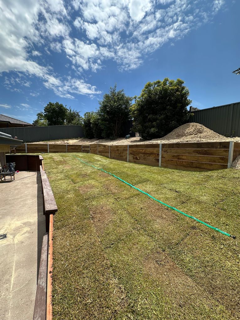 Completed timber retaining wall with new turf laid in a backyard, freshly turfed lawn