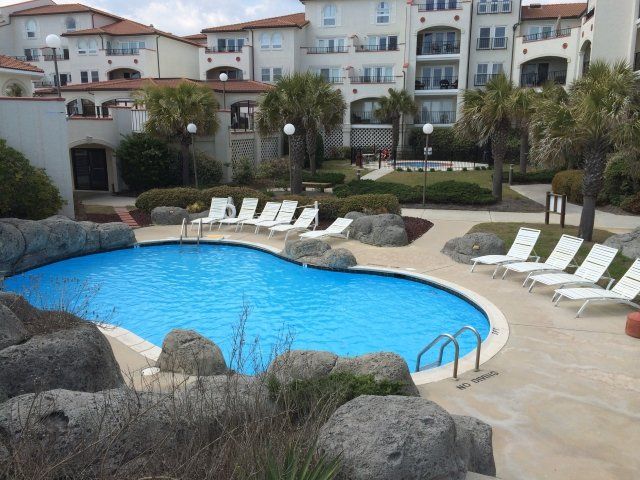 A large swimming pool surrounded by chairs and rocks