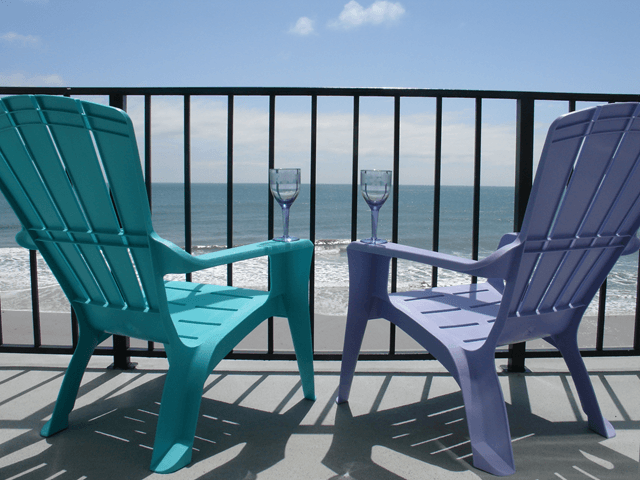 Two blue and purple chairs on a balcony overlooking the ocean