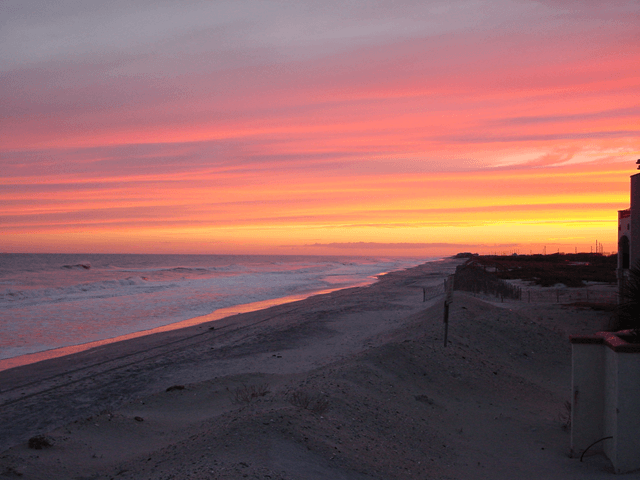 A beach with a sunset in the background