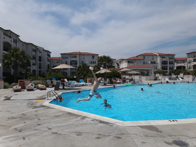 A man is jumping into a large swimming pool