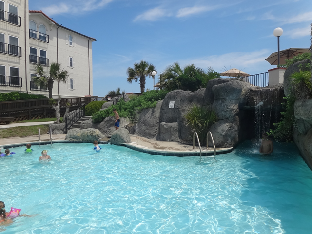 A large swimming pool with a waterfall in the middle of it