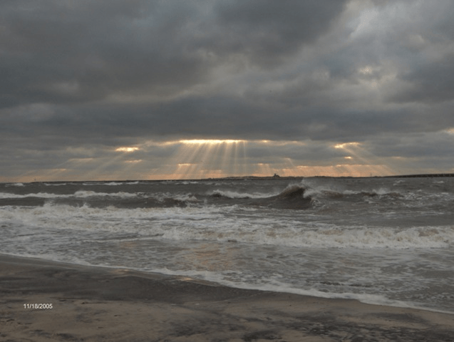 The sun shines through the clouds over the ocean