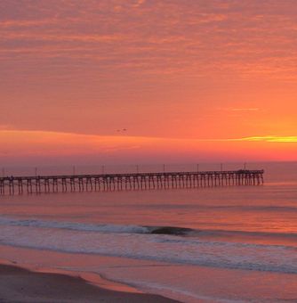 A sunset over the ocean with a pier in the foreground