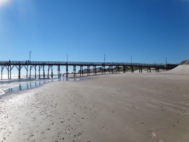 A beach with a pier in the background on a sunny day