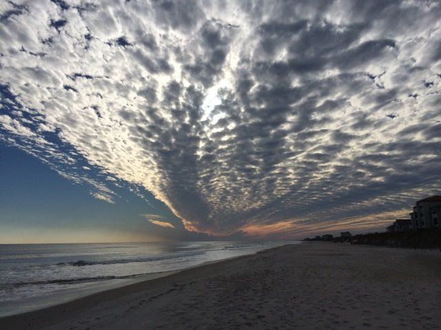 A cloudy sky over a beach at sunset
