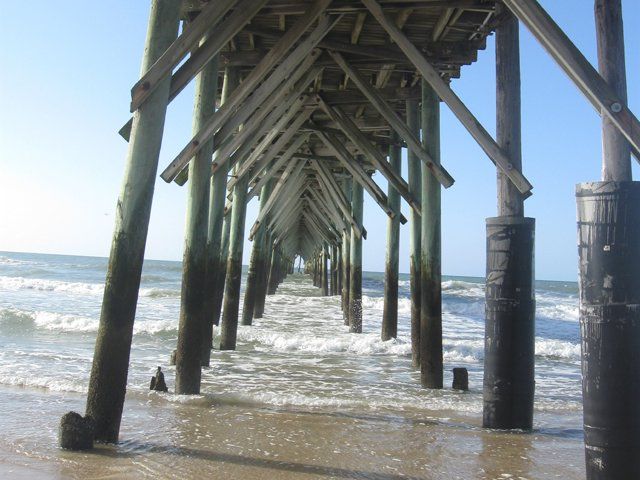 A pier going into the ocean with a blue sky in the background