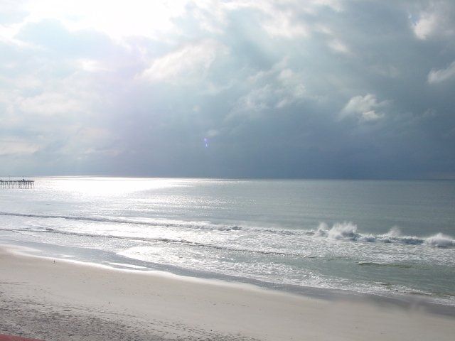 A beach with waves coming in on a cloudy day