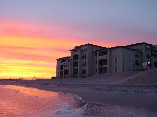 A sunset over a beach with a building in the background