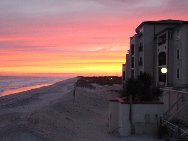 A sunset over the ocean with a building in the foreground