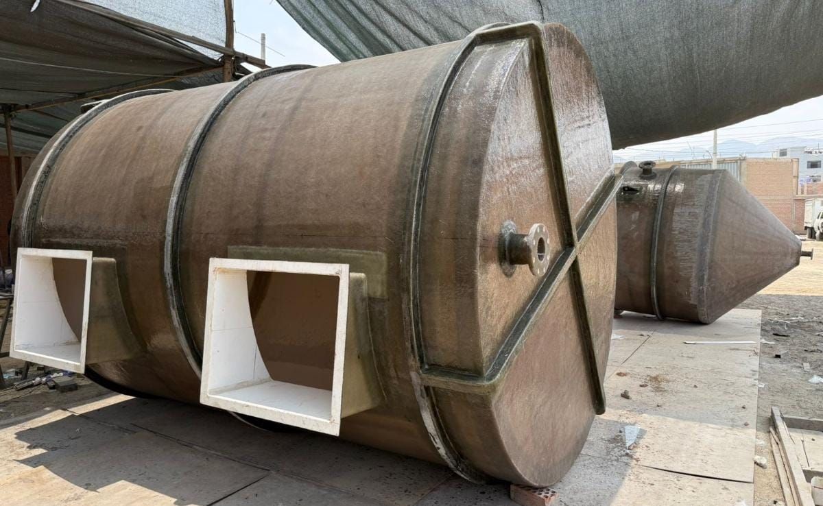 Gran sección de conducto o tanque industrial marrón con dos aberturas cuadradas blancas en el patio de un almacén.