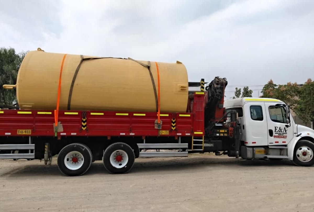 Camión blanco de plataforma plana que transporta un gran tanque cilíndrico color canela