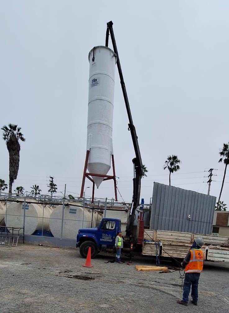 Tanque vertical blanco levantado con una grúa en una obra de construcción