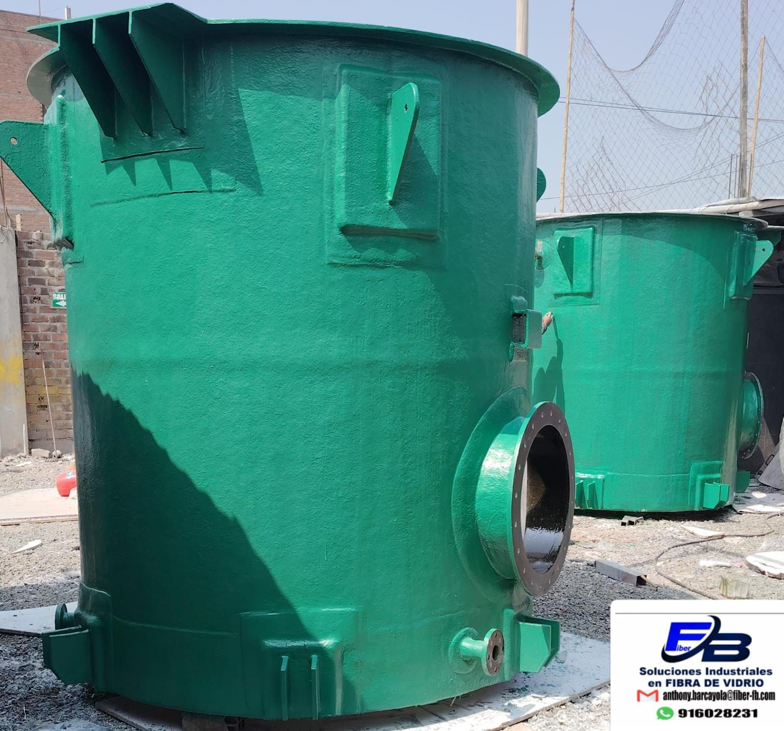 Tanque industrial verde con aberturas laterales para tuberías, mostrado al aire libre en un patio.