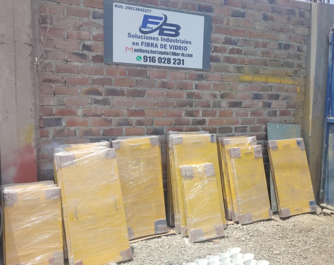 Pila de paquetes envueltos en papel amarillo junto a una pared de ladrillos con un letrero de F3.