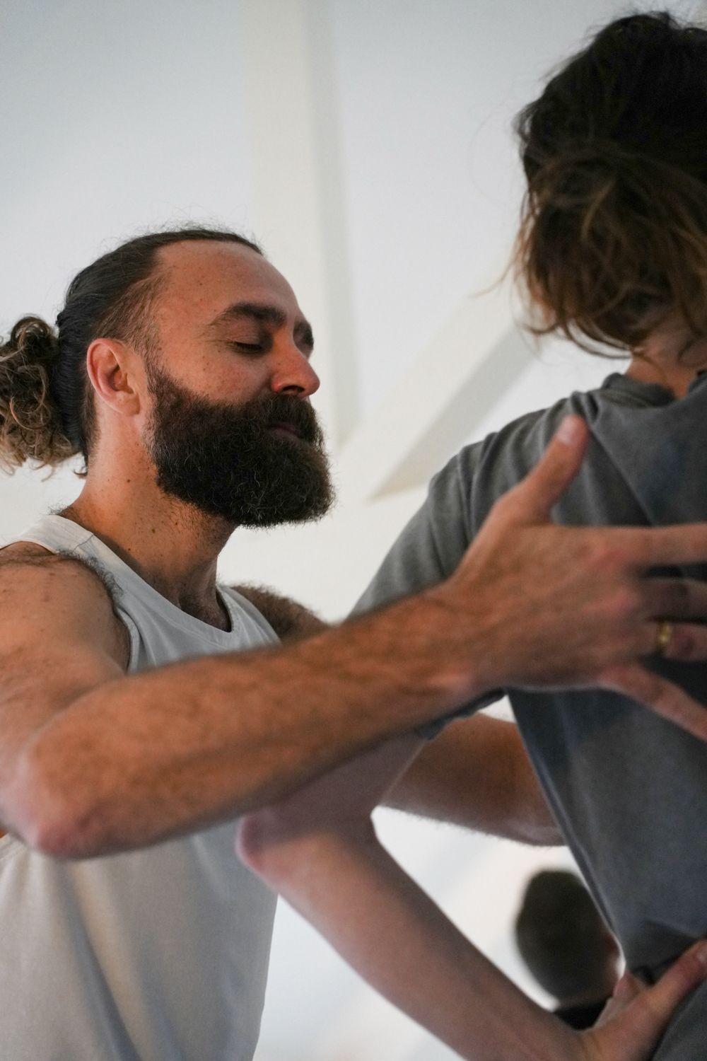 A male teacher works with a student doing yoga