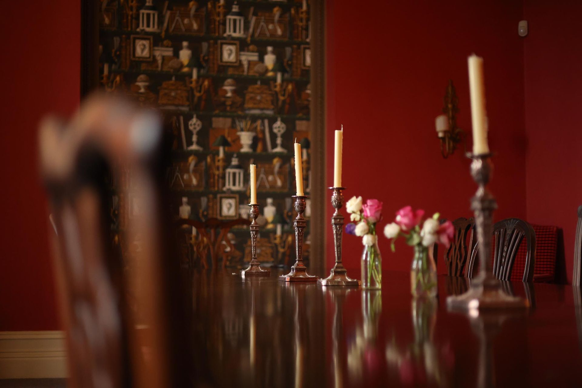 A dining room table with candles and vases of flowers on it.