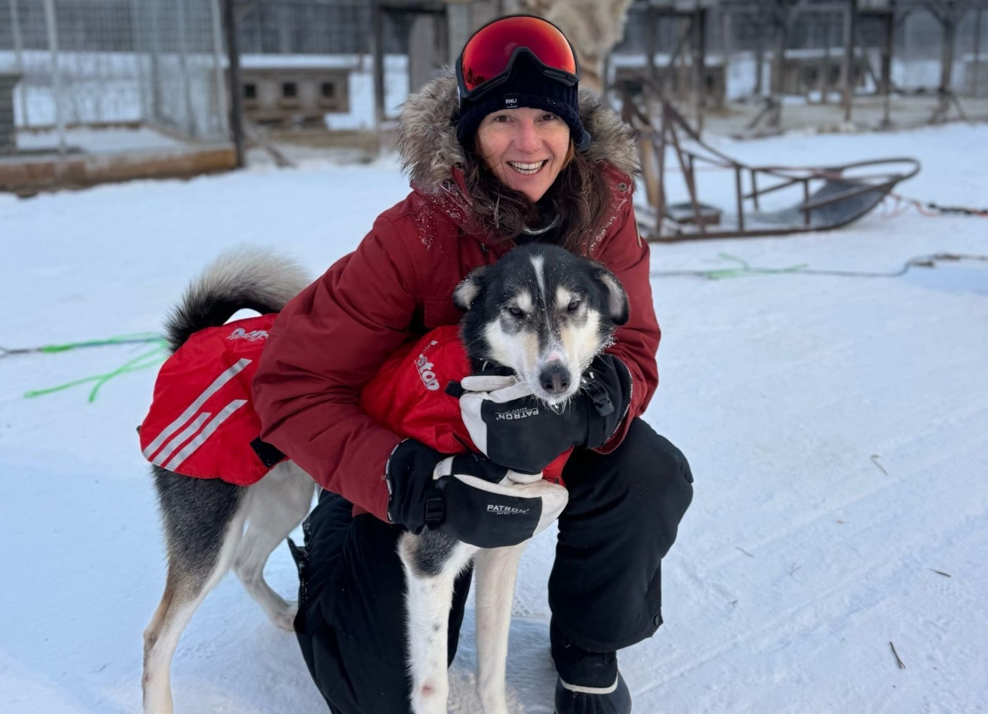 A person cuddling a husky dog in snow