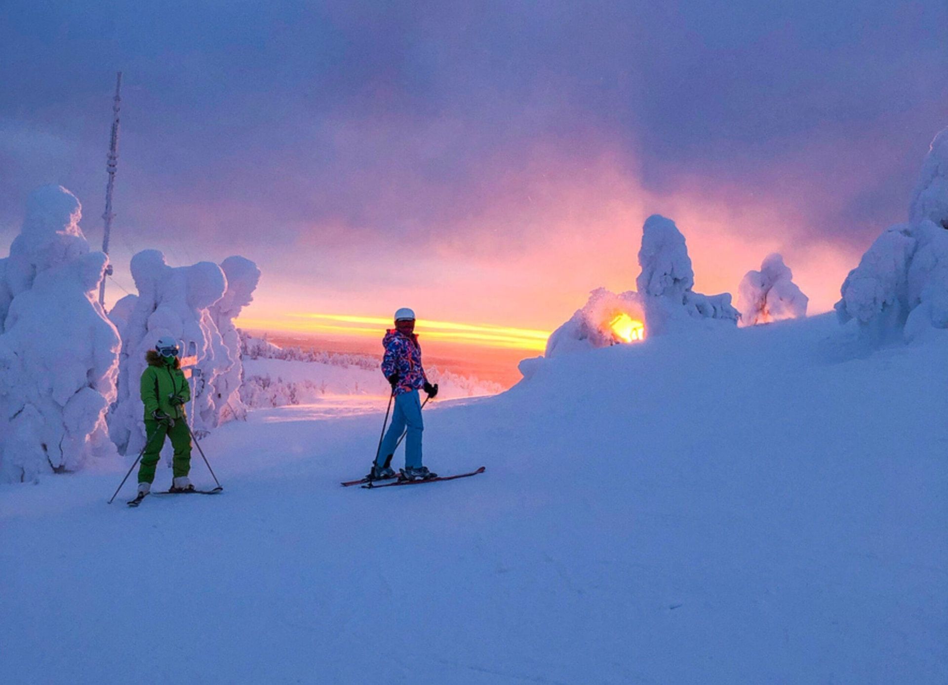 Two people skiing at sunrise