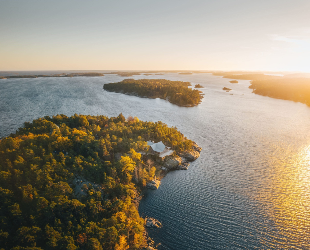 Aerial view of forested islands surrounded by calm water during a golden sunset.