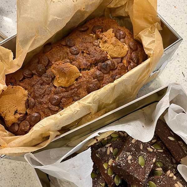 Banana bread with chocolate chips and peanut butter, next to a pan of brownies with seeds.