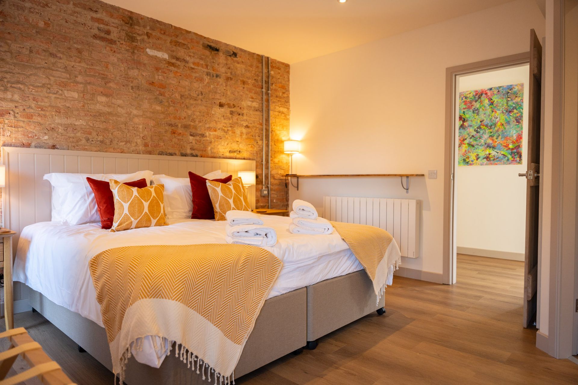 A bedroom with a large bed and a brick wall.