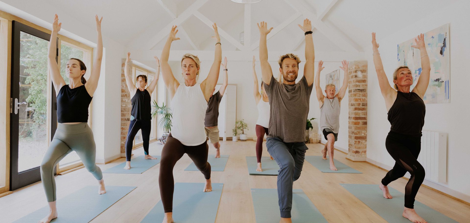 People practicing yoga indoors with arms raised.